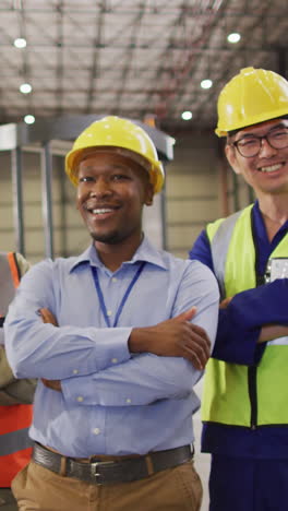 portrait of diverse workers wearing safety suits and smiling in warehouse