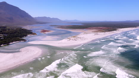 Wide-drone-view-over-Klein-River-lagoon-breaching-through-sandy-beach-into-ocean