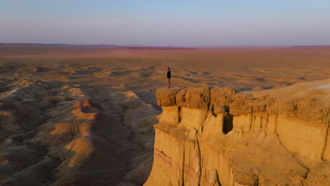 male tourist standing on the cliff at tsagaan suvarga white stupa of mongolia during sunset - drone shot