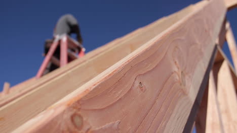 man hammers nails into a-frame cabin