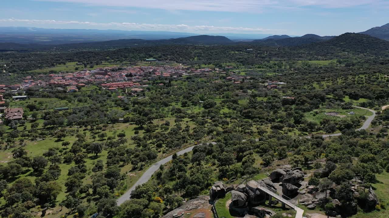 vuelo con un dron centrándose inicialmente en un punto de vista de roca con una pasarela y luego en una ciudad rural llamada pelahustan con un entorno impresionante de holm oaks y un paisaje sorprendente avila españa