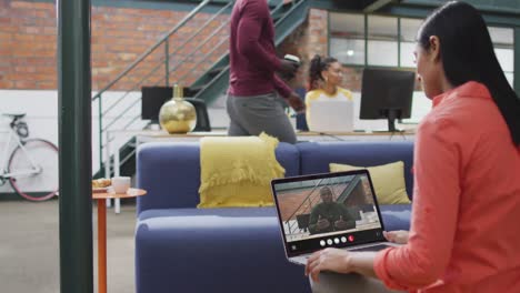 Mujer-Birracial-Usando-Una-Computadora-Portátil-Para-Videollamada,-Con-Un-Colega-De-Negocios-En-La-Pantalla