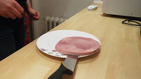 Cooked-ham-is-thrown-out-of-the-packaging-onto-a-plate