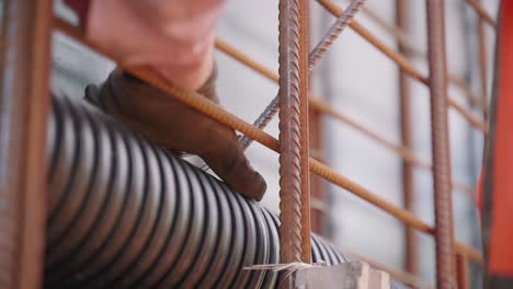 un trabajador atando un alambre para sujetar tuberías en un sitio de construcción