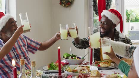 Fröhliche-Afroamerikanische-Familie-Mit-Mehreren-Generationen,-Die-Weihnachtsmützen-Trägt-Und-Das-Feiertagsessen-Feiert