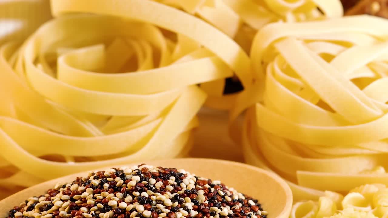 A close-up view of various grains and pasta arranged under warm lighting, highlighting textures and colors