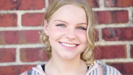 girl smiling outside against a brick wall