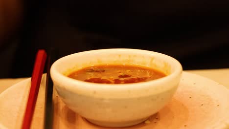 pouring sauce into a bowl of soup