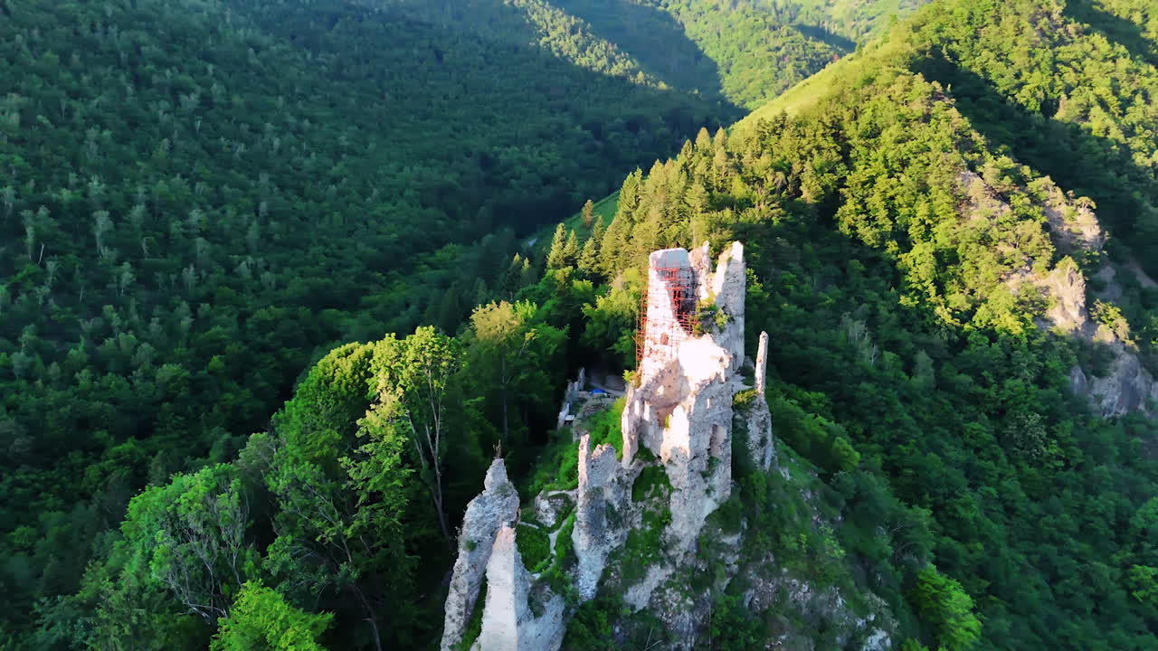 High rock with the ruins of the ancient castle on the top. Drone flight over the landmark in Slovakia. Beautiful Tatras around