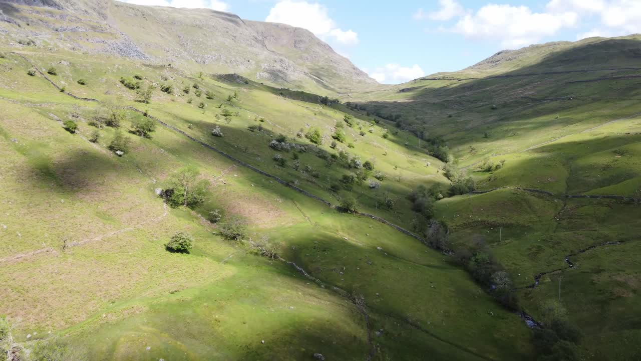 Vista soleggiata con drone del fondovalle dell'area di Kirkstone Pass con ombre di nuvole sui campi, guardando verso il Red Screes Fell in estate