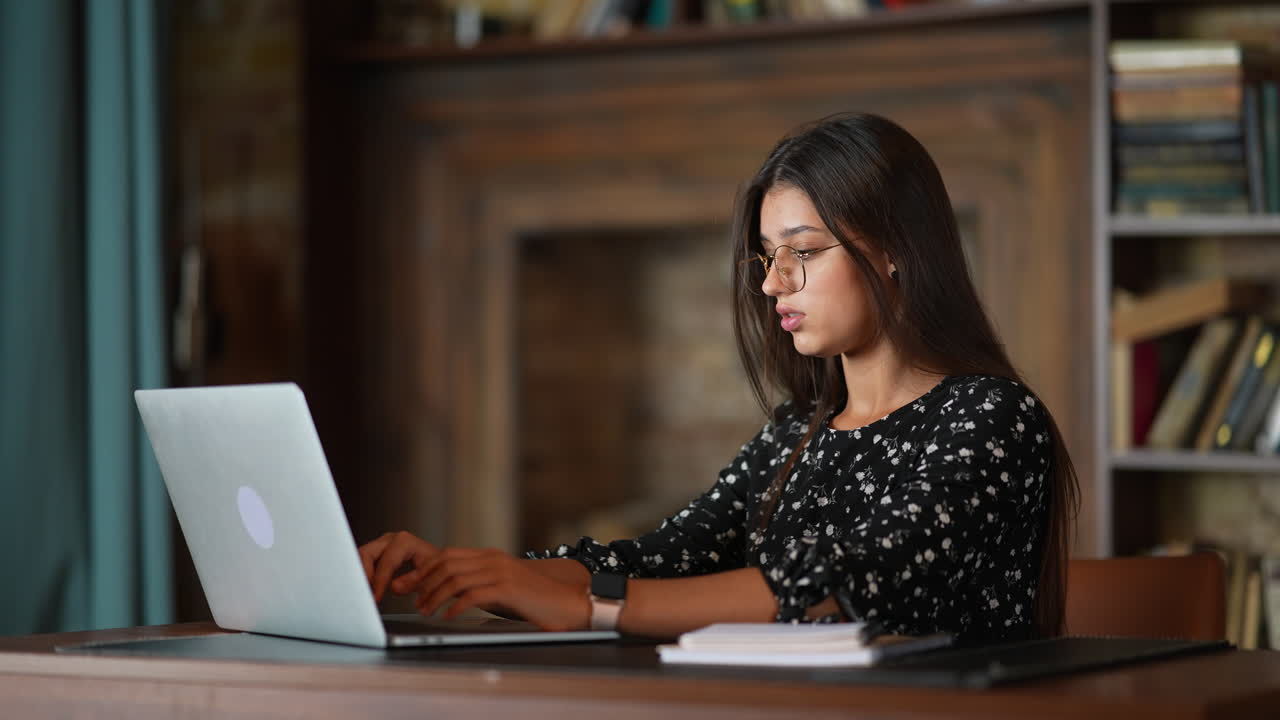 mujer trabajando en una computadora portátil en una biblioteca