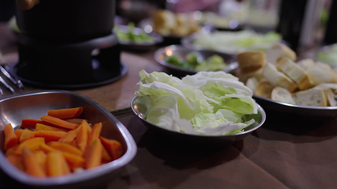 Plates of cabbage, carrots, celery, and sliced bread are arranged on a table, ready to be dipped in Bagna Cauda—a centuries-old Piedmontese garlic-anchovy sauce served hot in family gatherings.