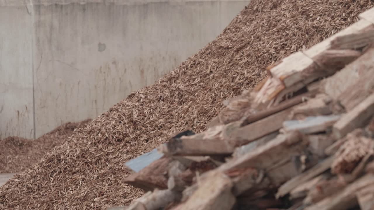 A pile of recycled wood next to a pile of wood chip at a processing plant