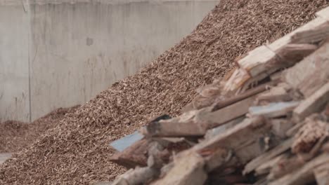 a pile of recycled wood next to a pile of wood chip at a processing plant