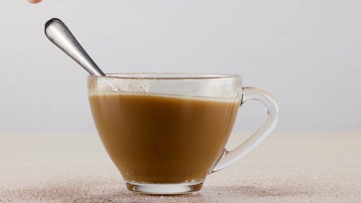Mano che mescola il caffè in una tazza di vetro