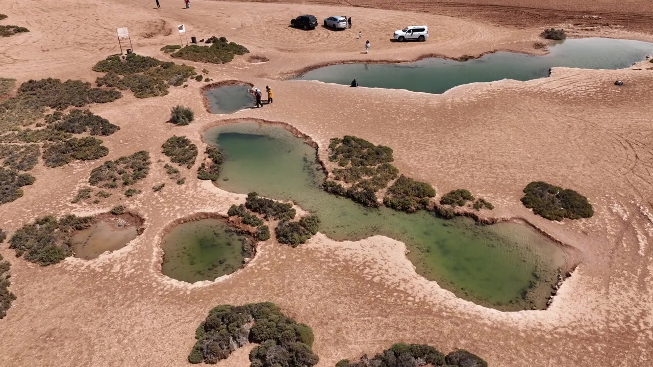 Dakhla, Morocco – [Month Day, Year]: Aerial drone view of visitors exploring a series of natural desert pools near Dakhla, a unique attraction in Morocco's Atlantic Sahara popular with travelers seeki