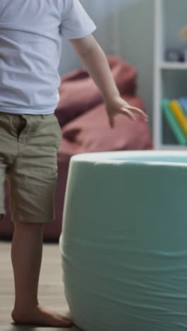 los hermanos pequeños recogen bolas de plástico y llenan la piscina seca en la sala de estar. el niño y la niña limpian el piso de los juguetes lanzando bolas en el cuenco en casa de cerca