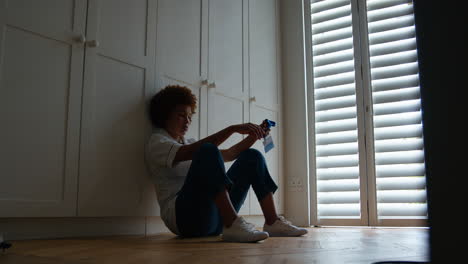 unhappy and demotivated nurse wearing uniform sitting on floor at home after long shift