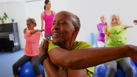 Front-view-of-Caucasian-female-trainer-training-senior-people-in-exercise-at-fitness-studio-4k