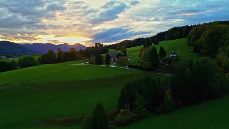 picturesque home in rolling grassy green hills of european countryside at sunset