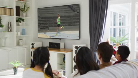 행복 한 가족 이 집 에서 함께 앉아서 tv 에서 장거리 점프 경기를 시청 하고 있다