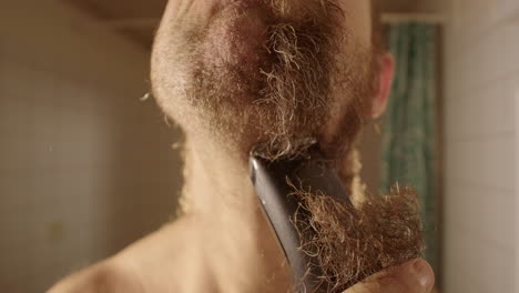 slow motion, wide, a man in bathroom shaves into the lens with clippers