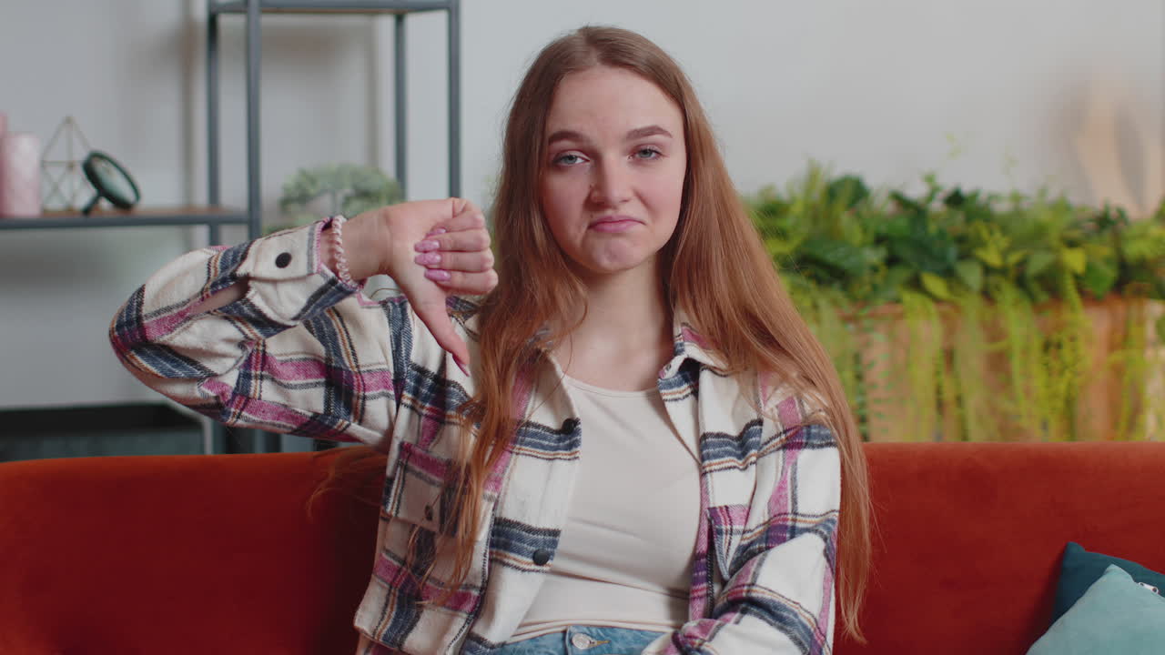Teen girl showing thumbs down sign gesture, expressing discontent, disapproval, dissatisfied dislike