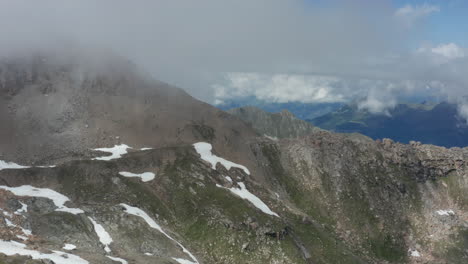 aerial of rocky mountain slope with thick, dark clouds forming