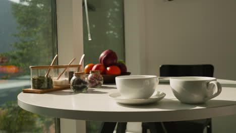 tazas, ingredientes de té y frutas en la mesa. composición con tazas de cerámica pequeños frascos de especias y hierbas secas. postre saludable en la cocina