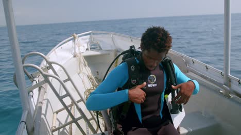 scuba diver straps on tank and buoyancy control device before diving into the indian ocean in kenya