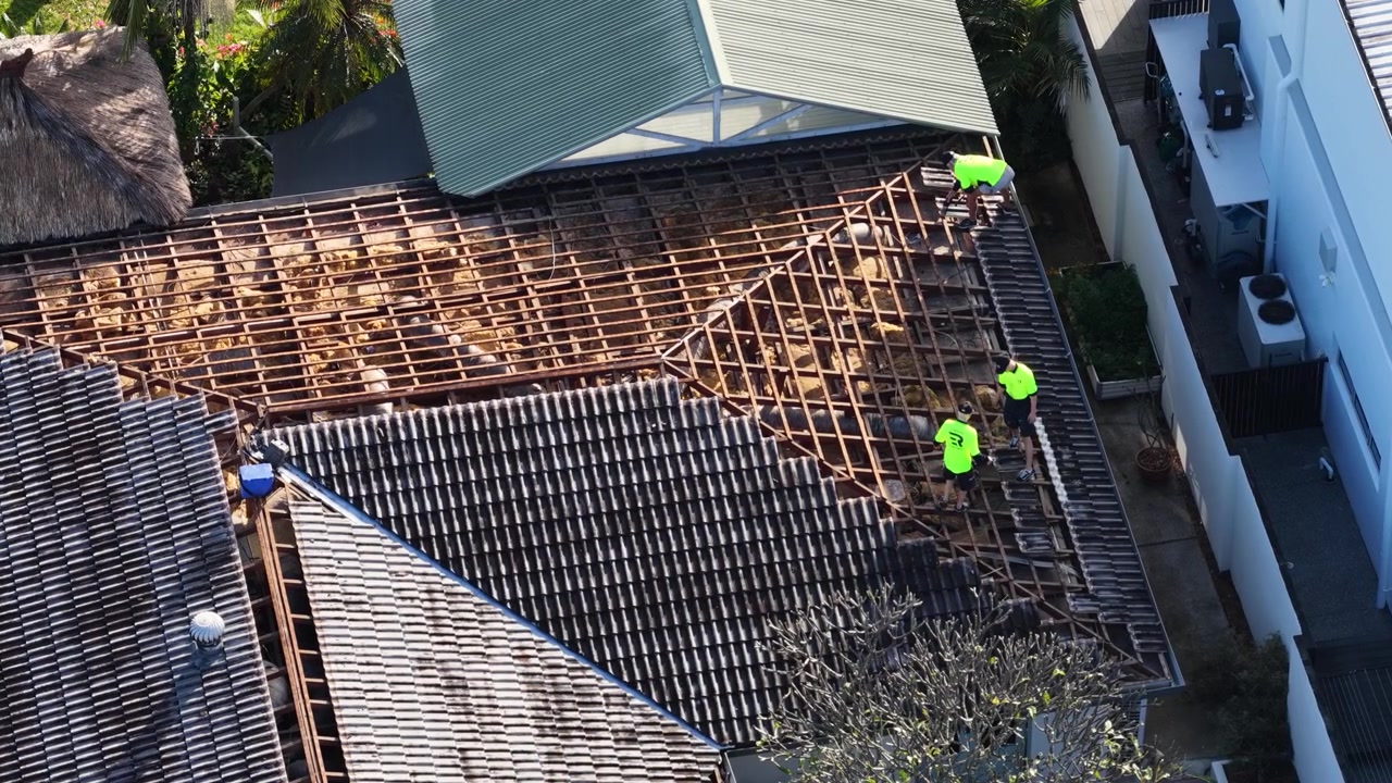 Aerial view of contractors repairing a tiled roof on a sunny day in Broadbeach.