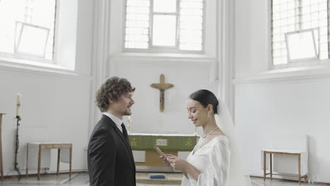 pareja usando el teléfono durante la ceremonia de bodas en la iglesia