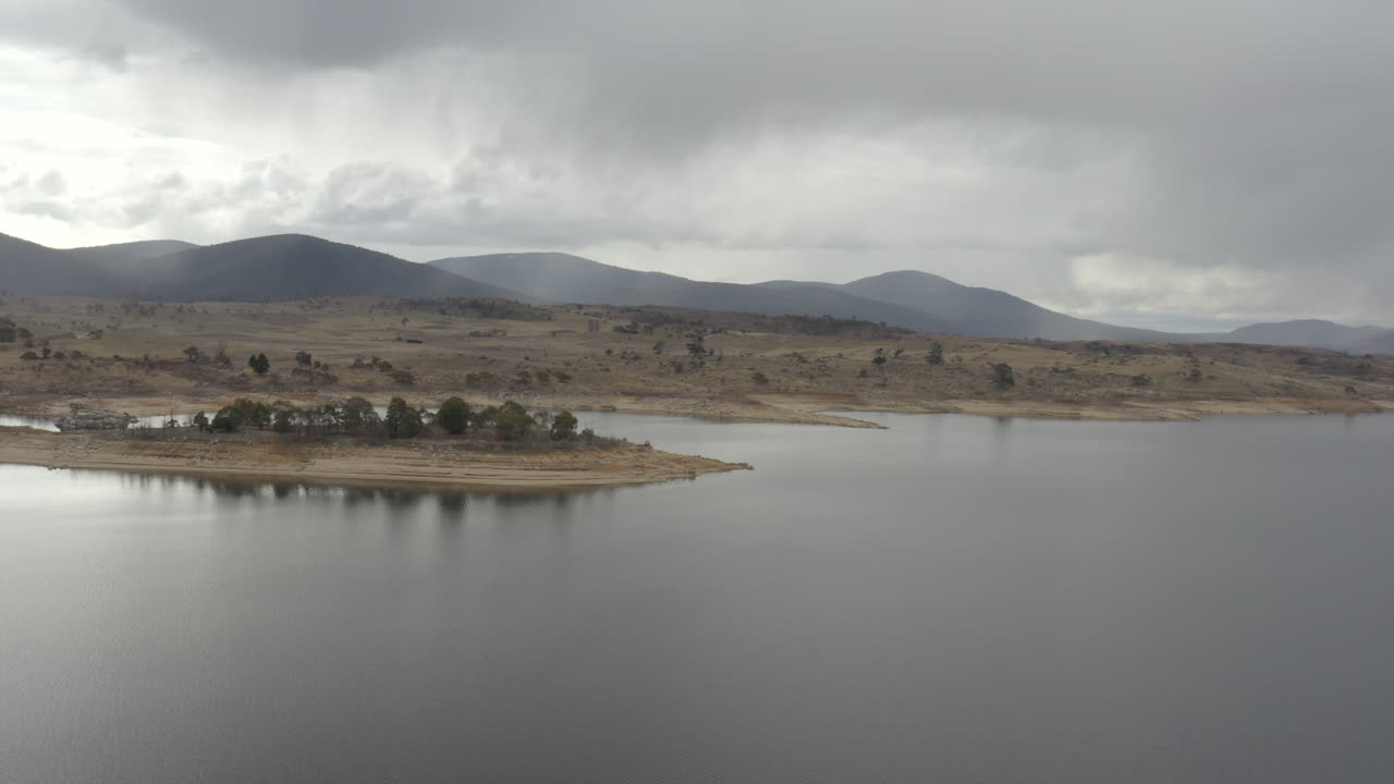 tomada de avión no tripulado de la costa y las montañas distantes alrededor del lago jindabyne en un día nublado de invierno