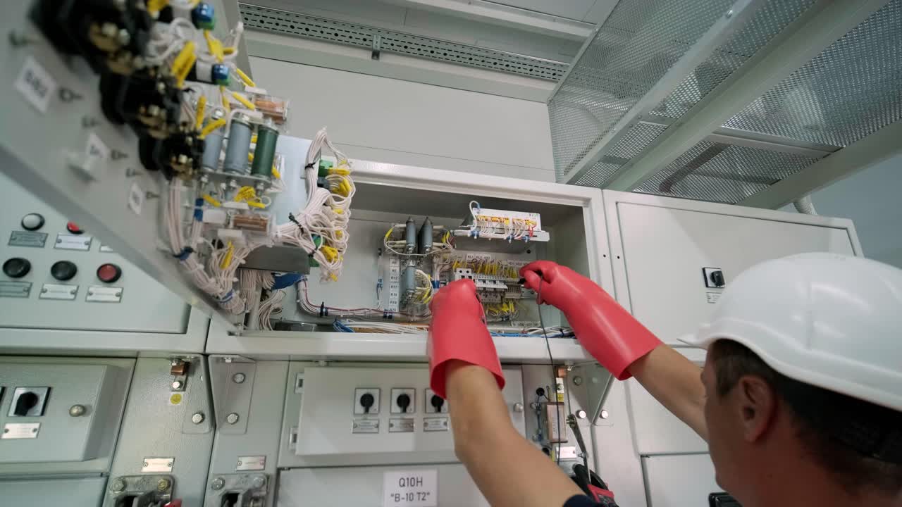 el ingeniero eléctrico que trabaja comprueba la tensión de corriente eléctrica y la sobrecarga en la parte delantera del gabinete del centro de carga o de la unidad de consumo para el mantenimiento en la sala principal del sistema de distribución de energía.