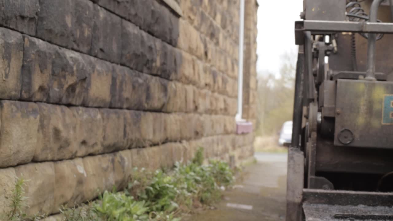 Heavy plant industrial parked on urban sidewalk panning shot