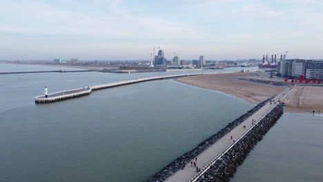 Entrada-Al-Puerto-De-La-Ciudad-De-Ostende-Y-Gente-Caminando-En-El-Muelle,-Antena