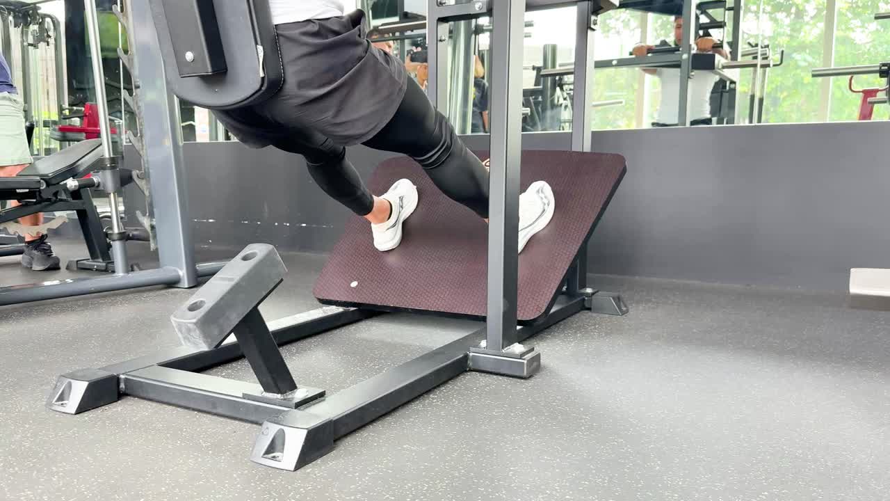 Athletic man uses leg press machine in bright gym, natural daylight, static camera, strength training
