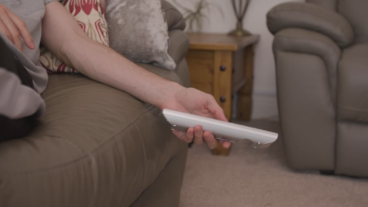 tv 리모컨으로 소파에 게으르게 매달려 있는 손