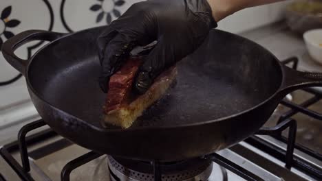 cierre las manos del chef, poniendo bistecs de carne encima de una sartén caliente para asar a la parrilla