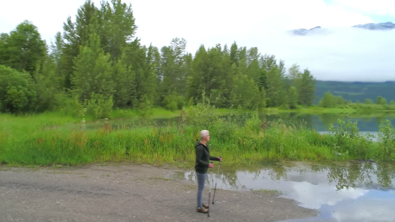 vista aérea de una mujer madura de pie cerca de un lago 4k