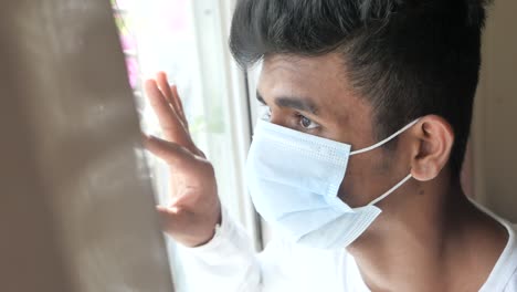 young person looking through a window while wearing a mask