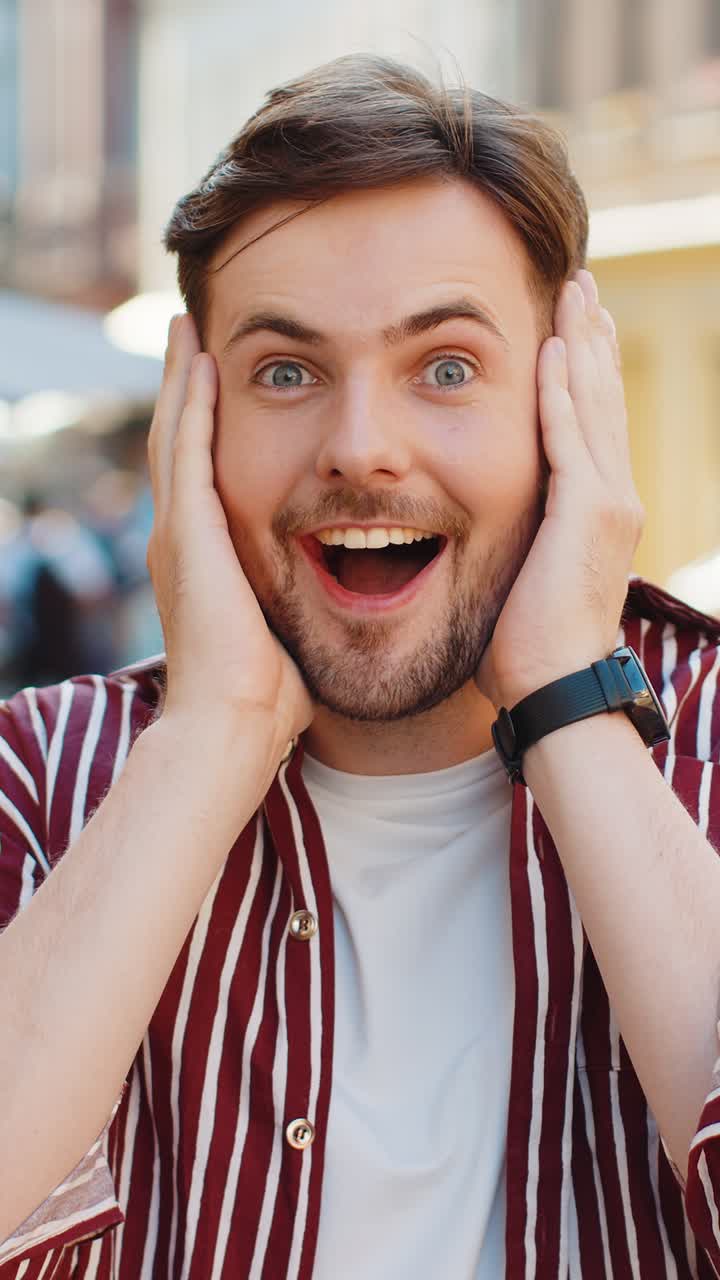 Adult man looking surprised at camera shocked by sudden win good victory news wow in city street