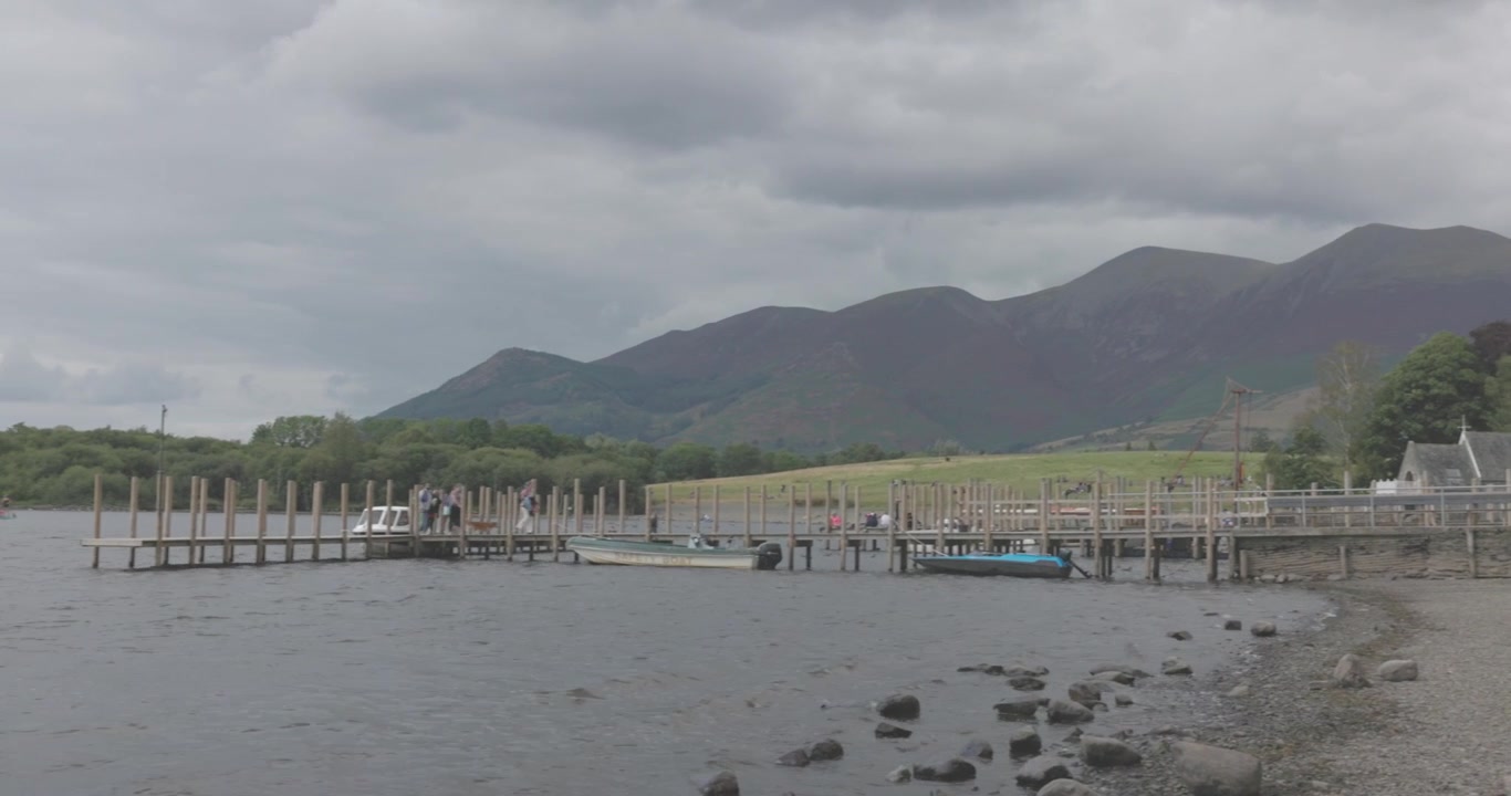 bidikan panning wisatawan yang berjalan di sepanjang dermaga kayu di Danau Windermere
