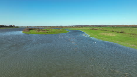 scenic island on river meuse - lush greenery amidst flowing water surrounded by serene landscape