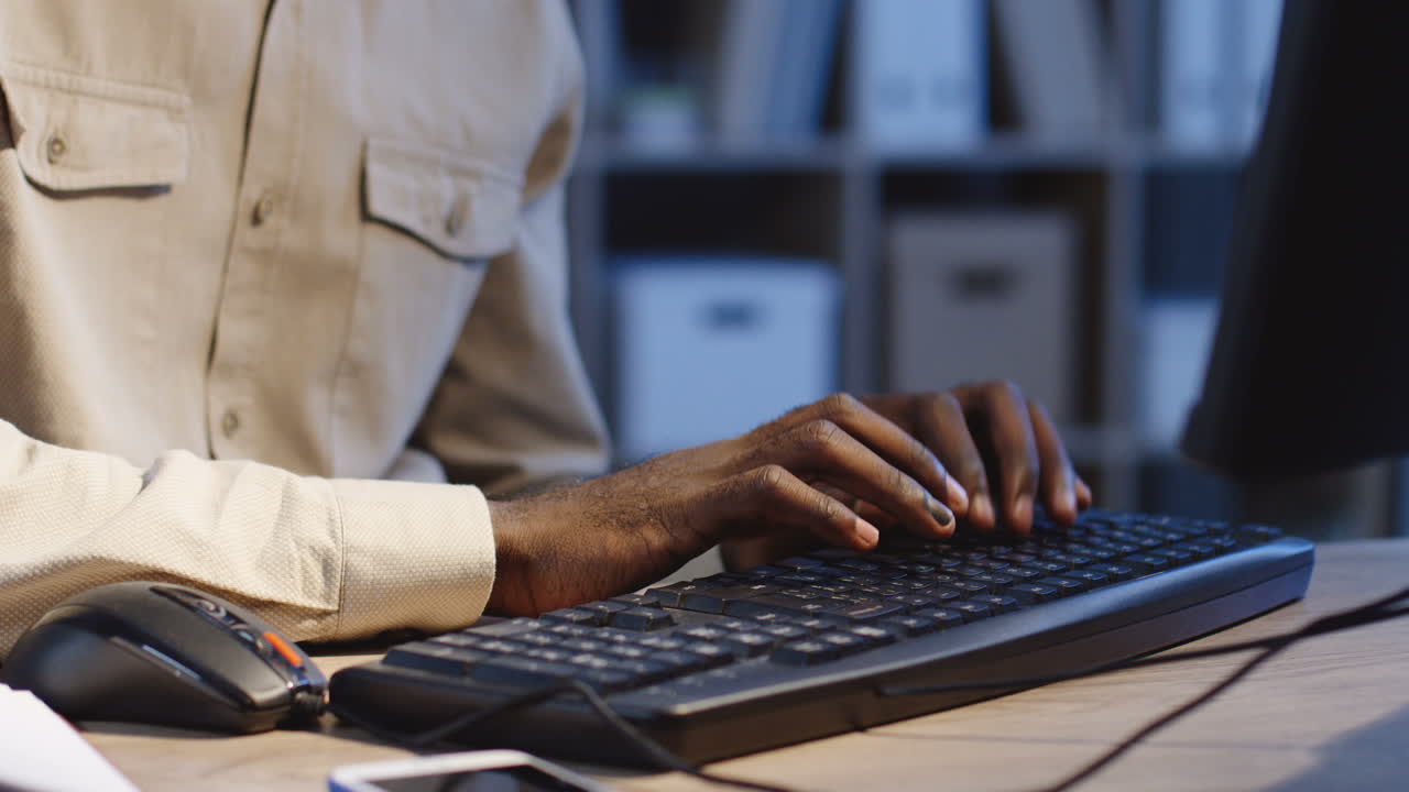 Close Up View Of Man's Fingers Texting On The Black Keyboard Of The Computer In The Office At Night