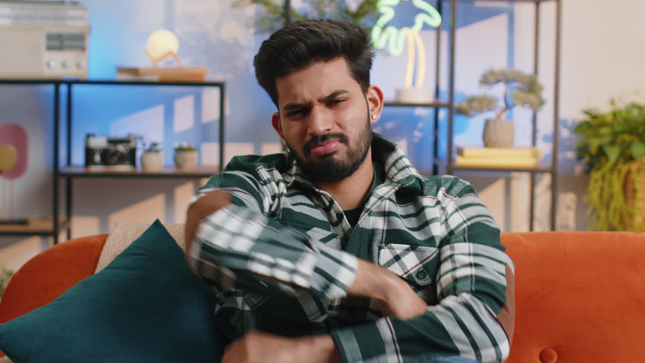 Upset indian man showing thumbs down dislike bad work disapproval dissatisfied feedback at home