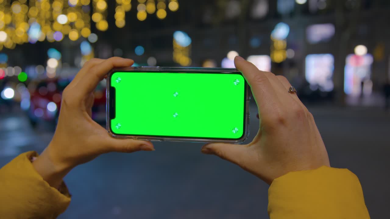 persona sostiene el teléfono inteligente horizontalmente en la ciudad nocturna