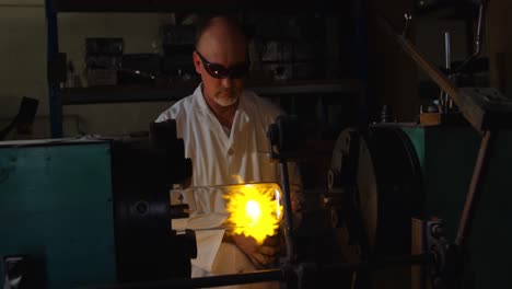 Front-view-of-mature-male-worker-creating-glass-in-glass-factory-4k