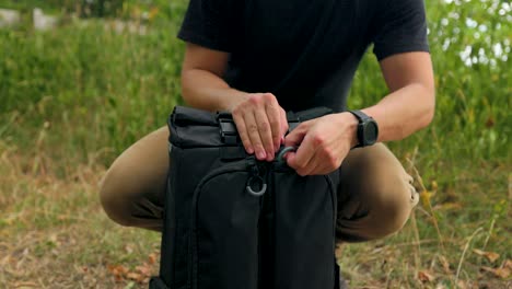 hiker opens a backpack zipper outdoors in a forest landscape setting