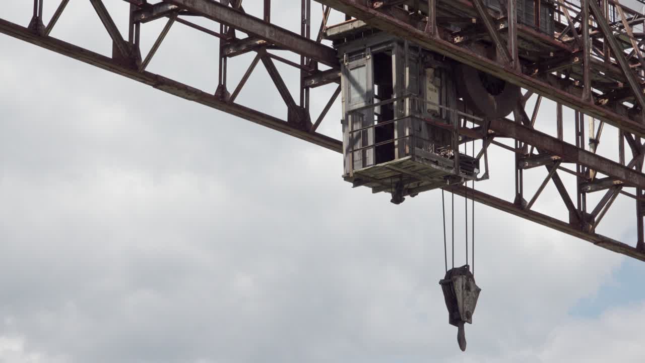 Zooming out of part of a crane used to transport marble blocks on an overcast day.